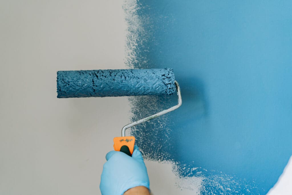 Roller applying fresh paint to interior wall
